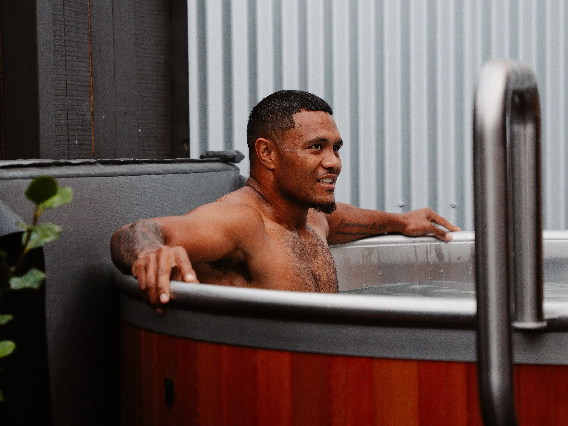 A member sitting chest-deep in the eight-person ice bath, arms resting over the rim.